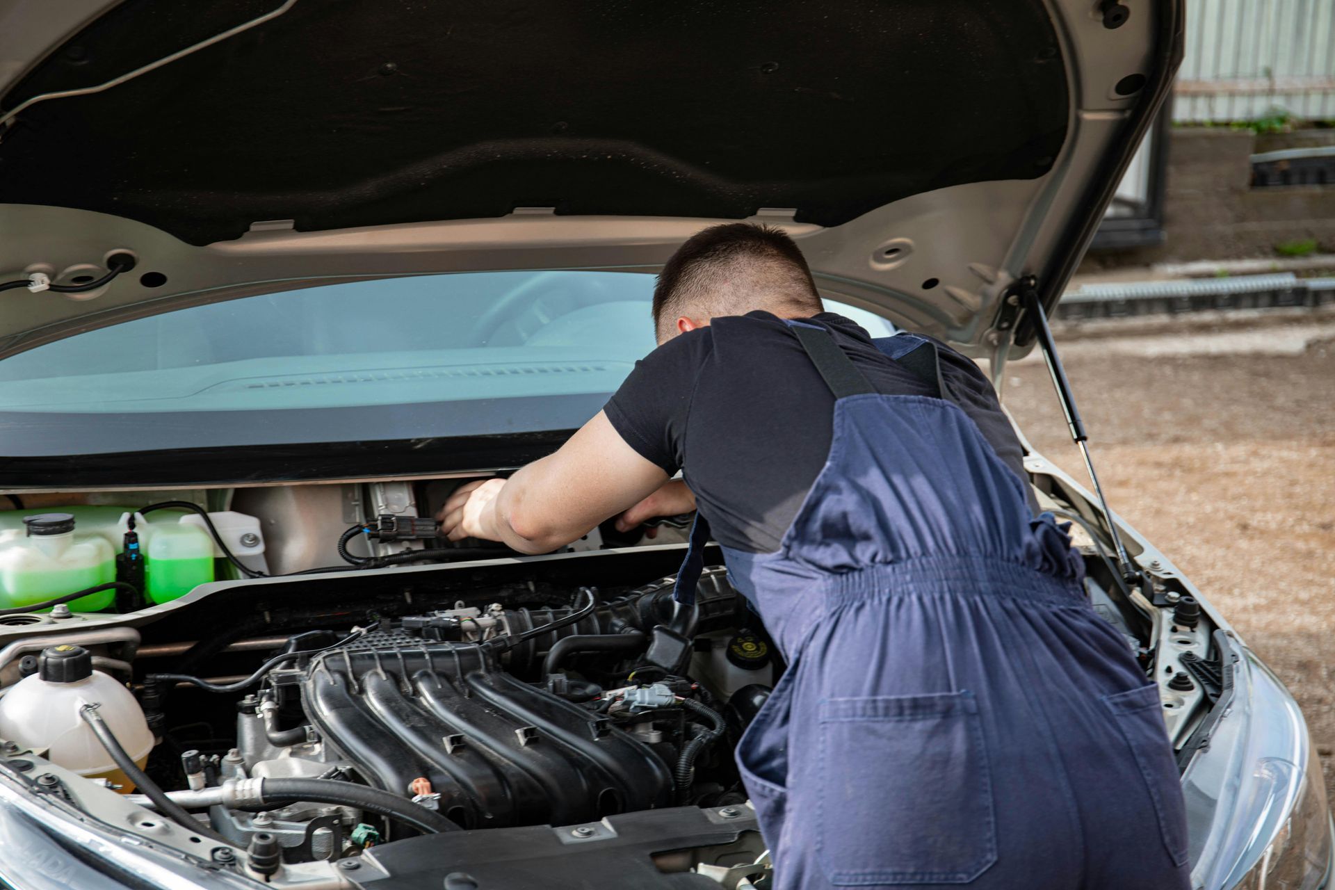 A man is working on the engine of a car with the hood open.