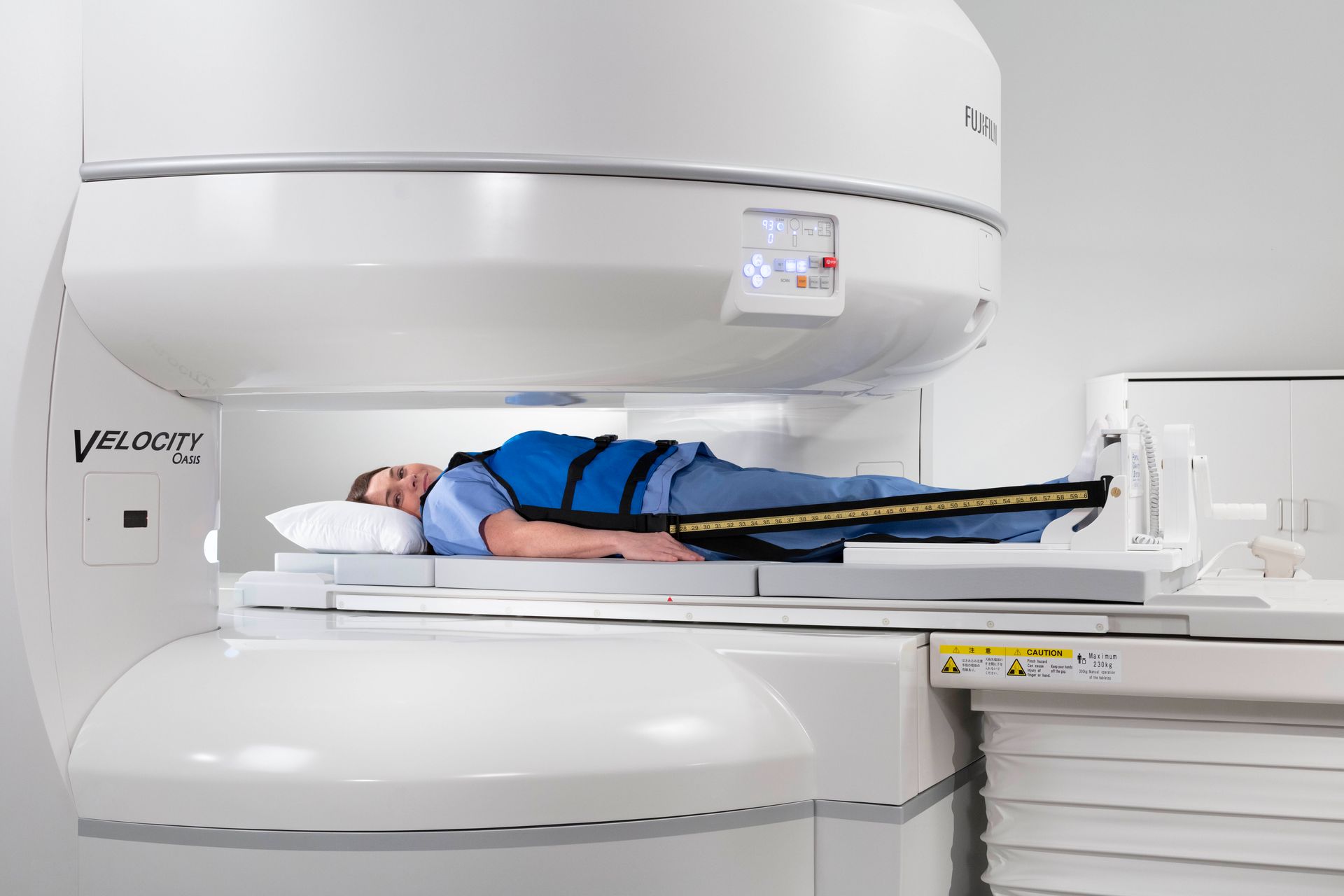 A man is standing next to a mri machine in a hospital room.