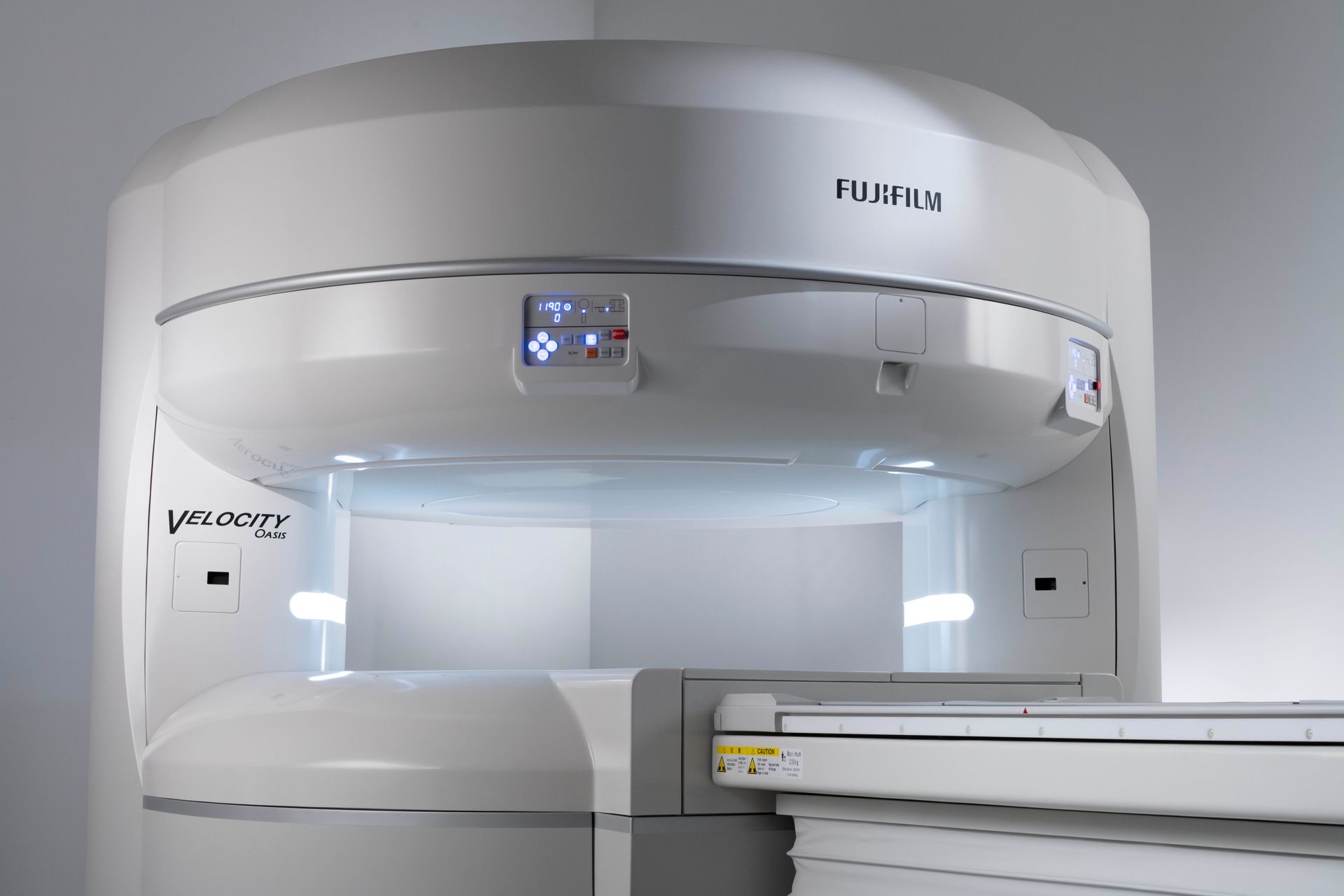 A fujifilm mri machine is sitting in a corner of a room.