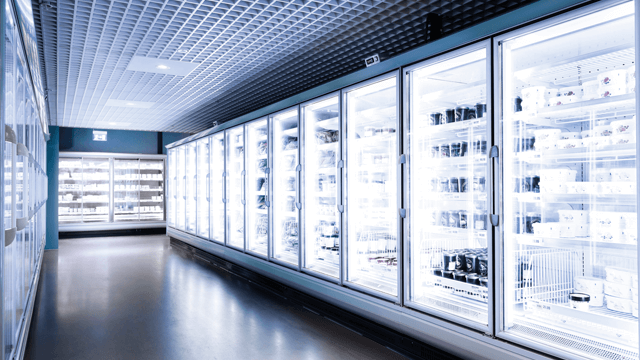 A long row of refrigerated glass doors in a brightly lit grocery store.