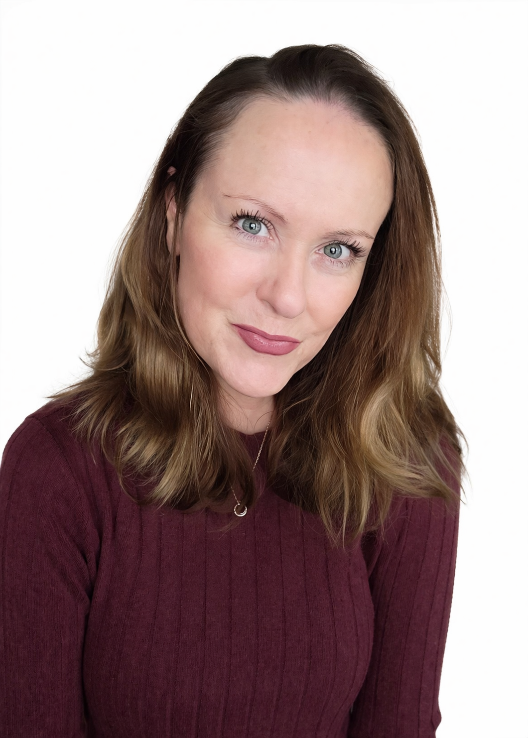 Portrait of a woman with long brown hair, wearing a maroon sweater against a white background