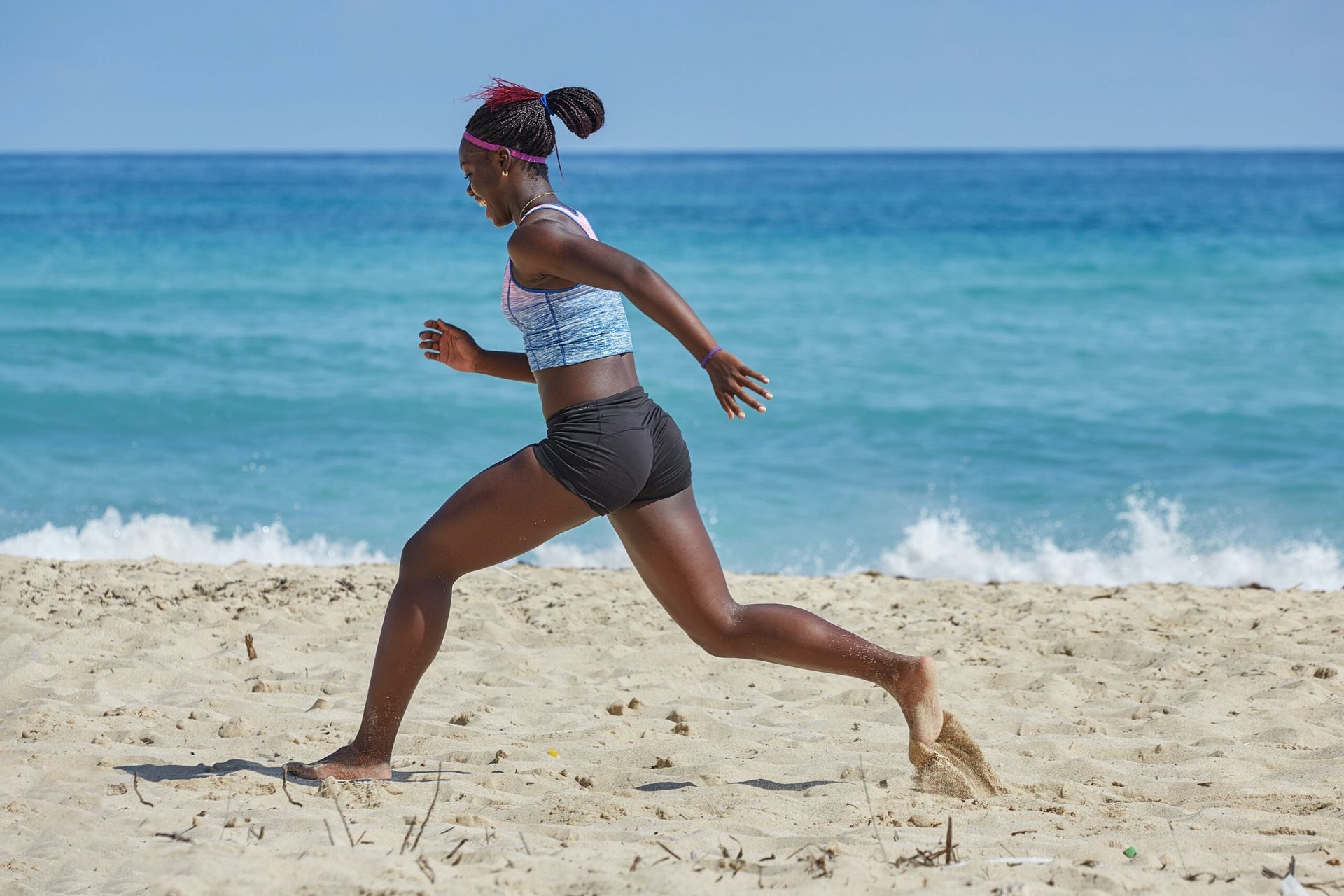Woman running on sandy beach toward ocean.
