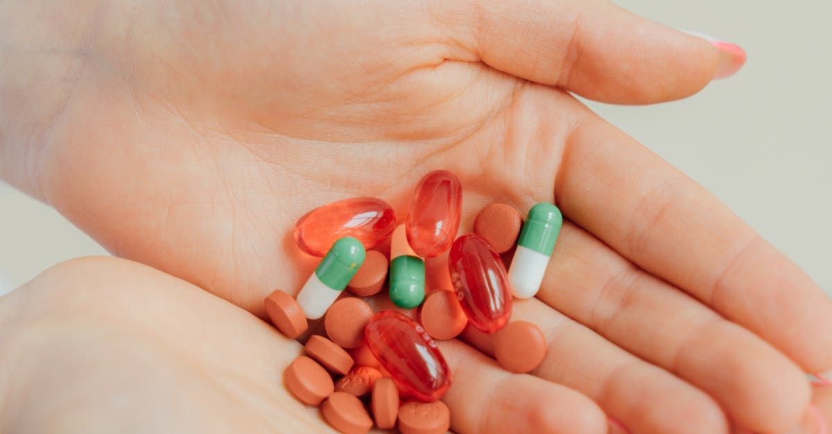 Hands holding a mix of colorful pills and capsules.
