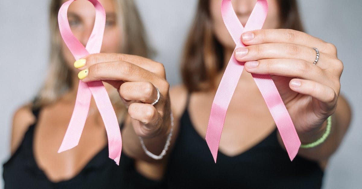 Two women holding pink breast cancer awareness ribbons.