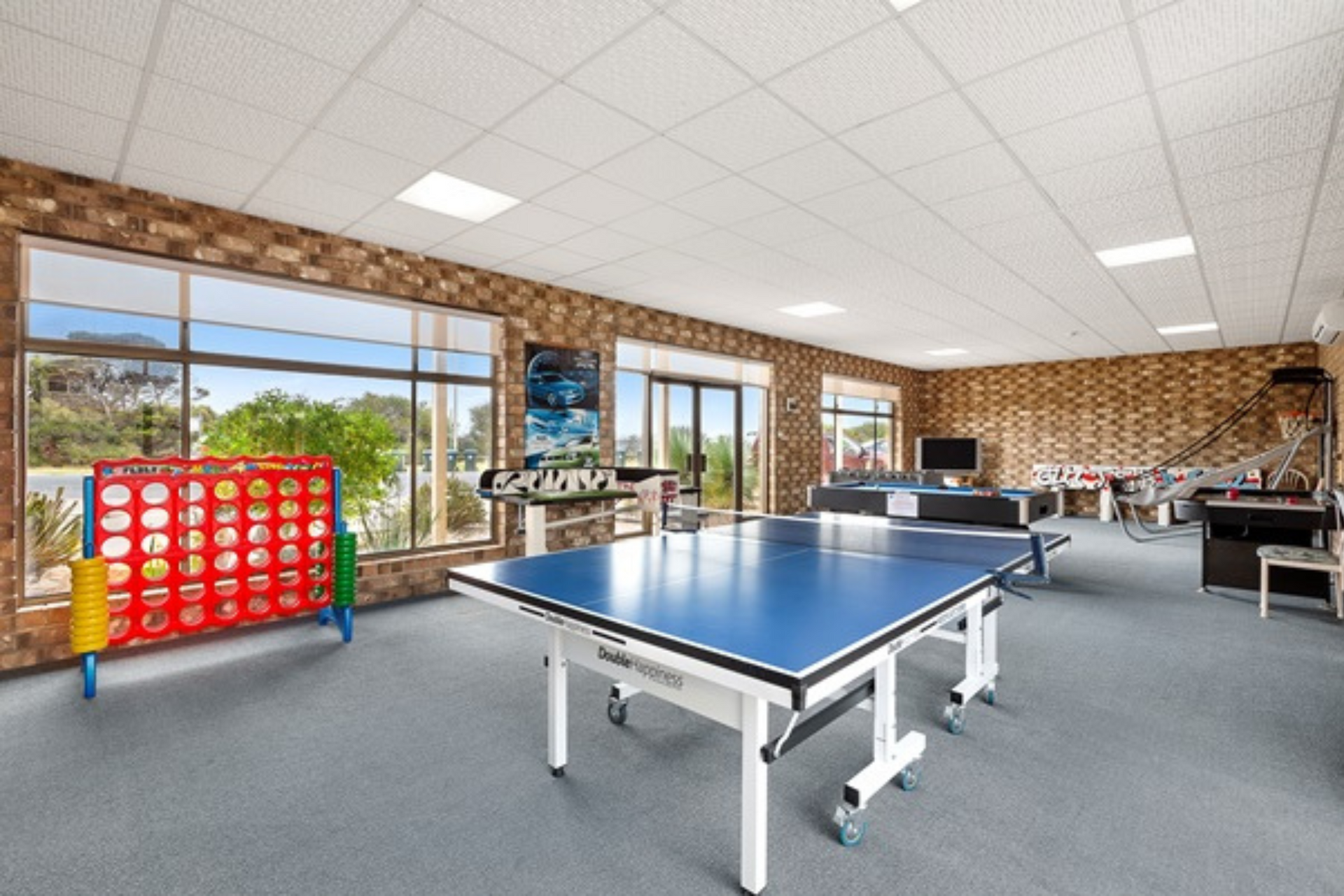 A large room with a ping pong table and a connect four game.