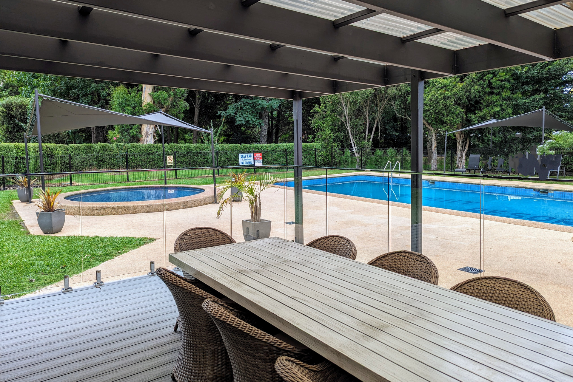 A table and chairs are sitting under a pergola next to a swimming pool.