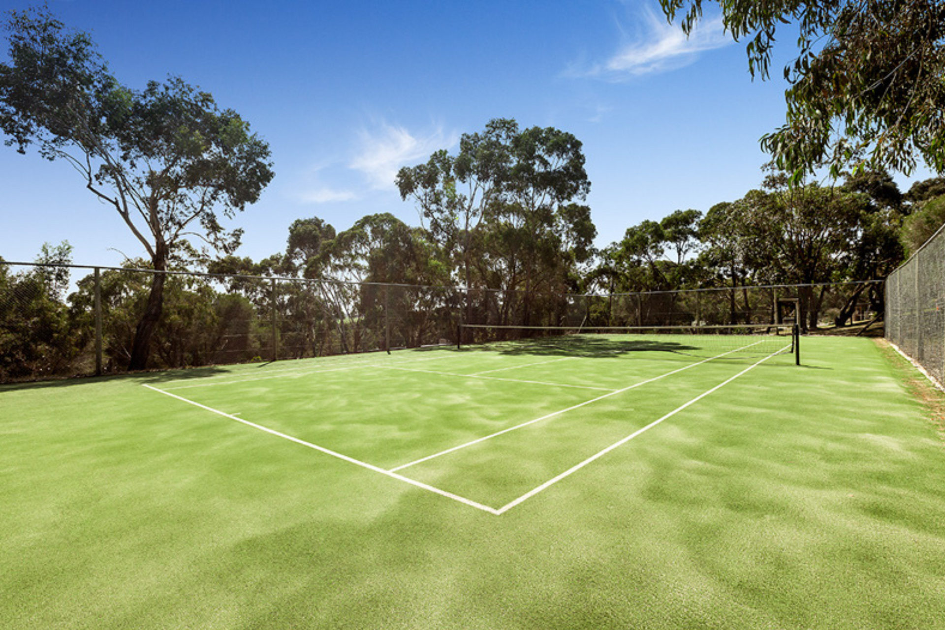 A tennis court with trees in the background on a sunny day