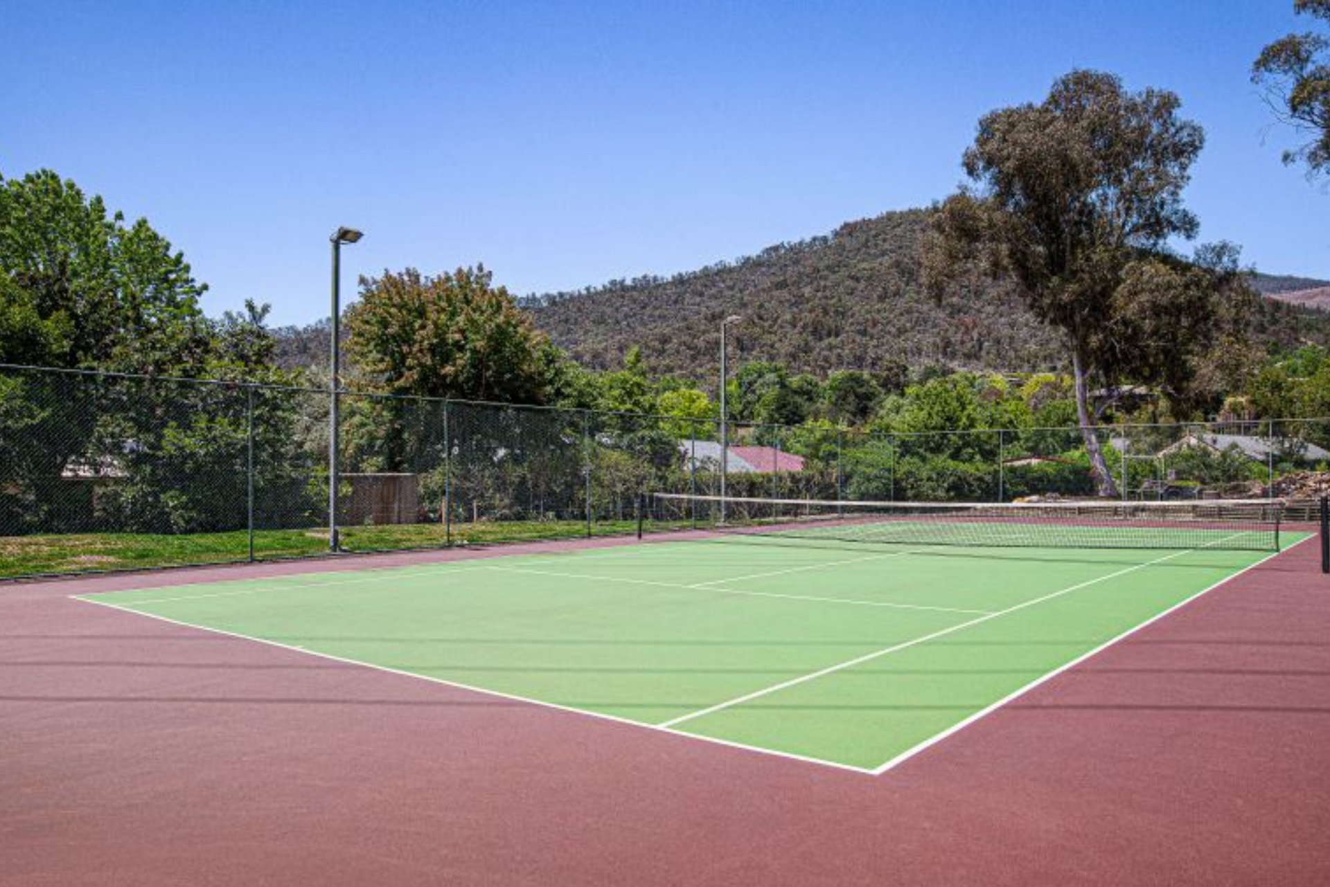 A tennis court with a fence and trees in the background
