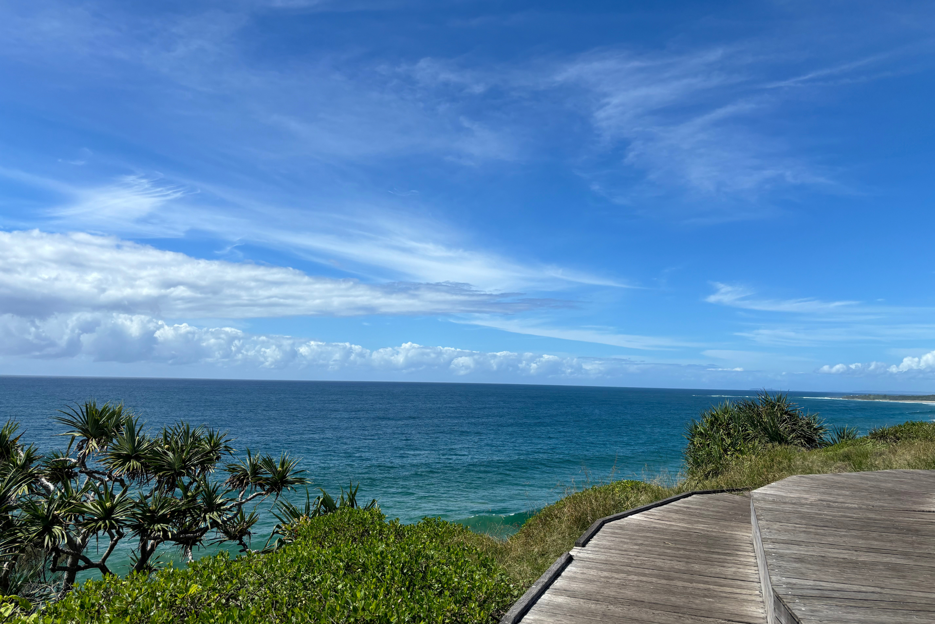 A wooden walkway leading to the ocean on a sunny day.