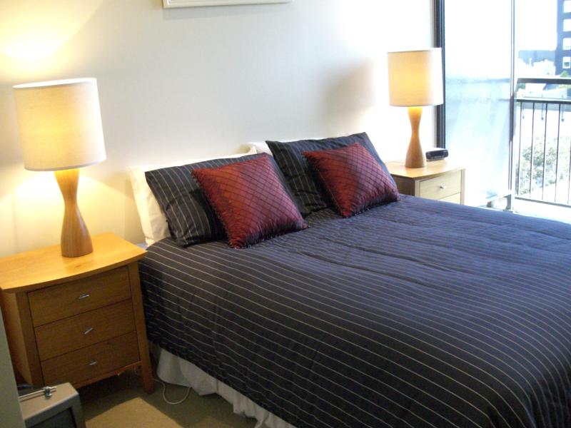 A bedroom with a bed two lamps and a balcony