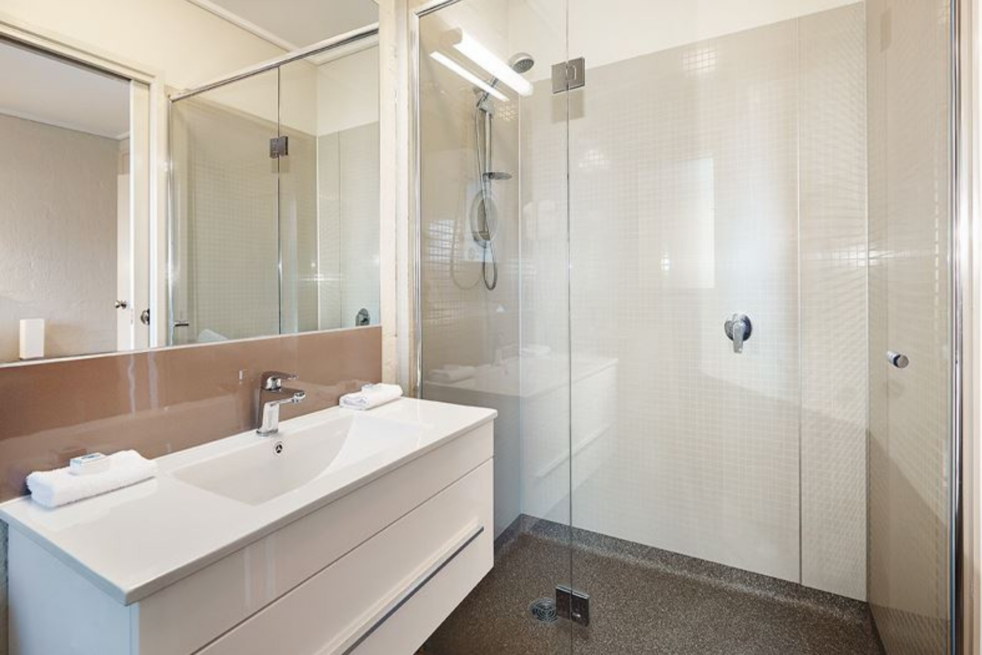 A bathroom with a sink , mirror and walk in shower.