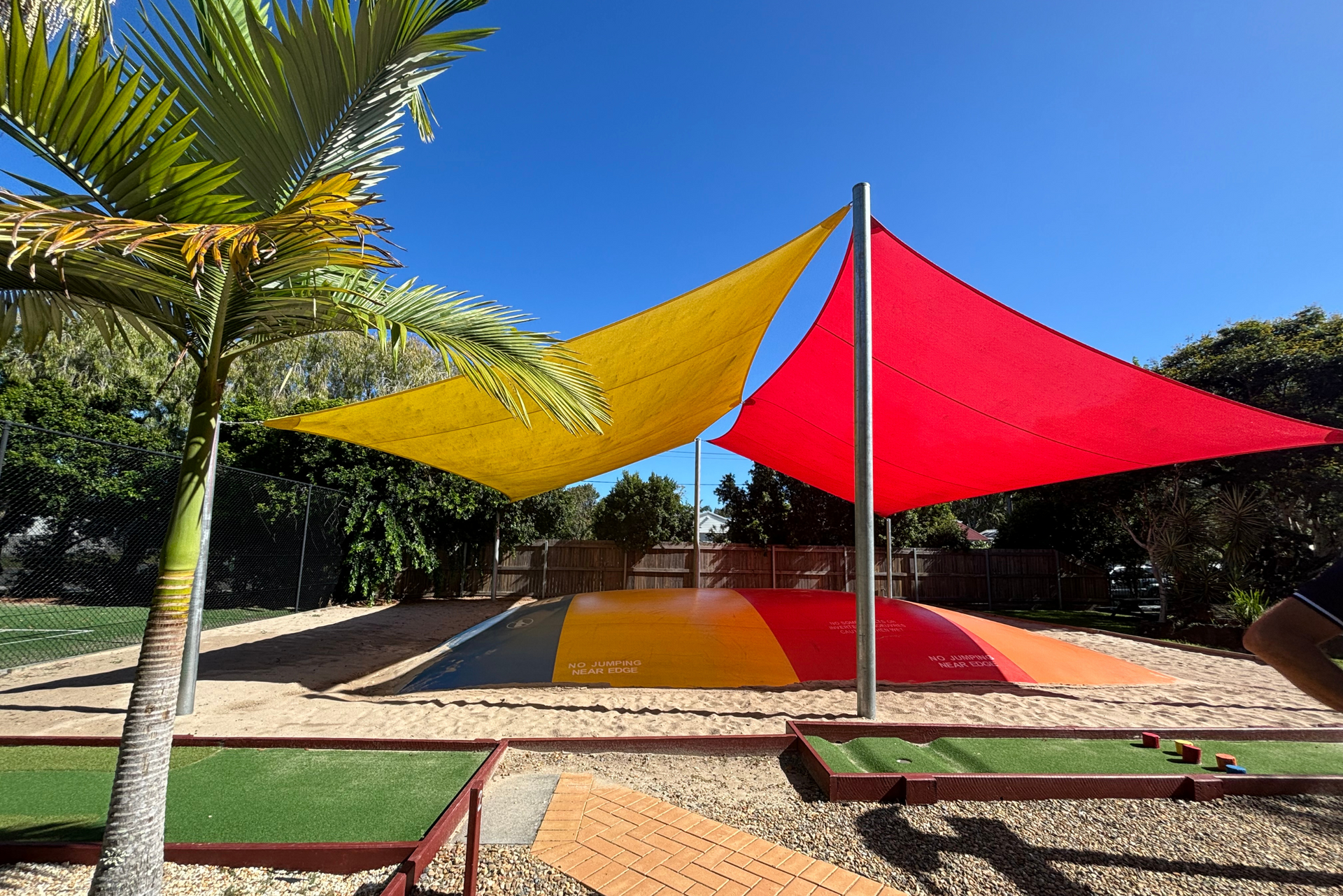 A playground with a red , yellow and orange umbrella