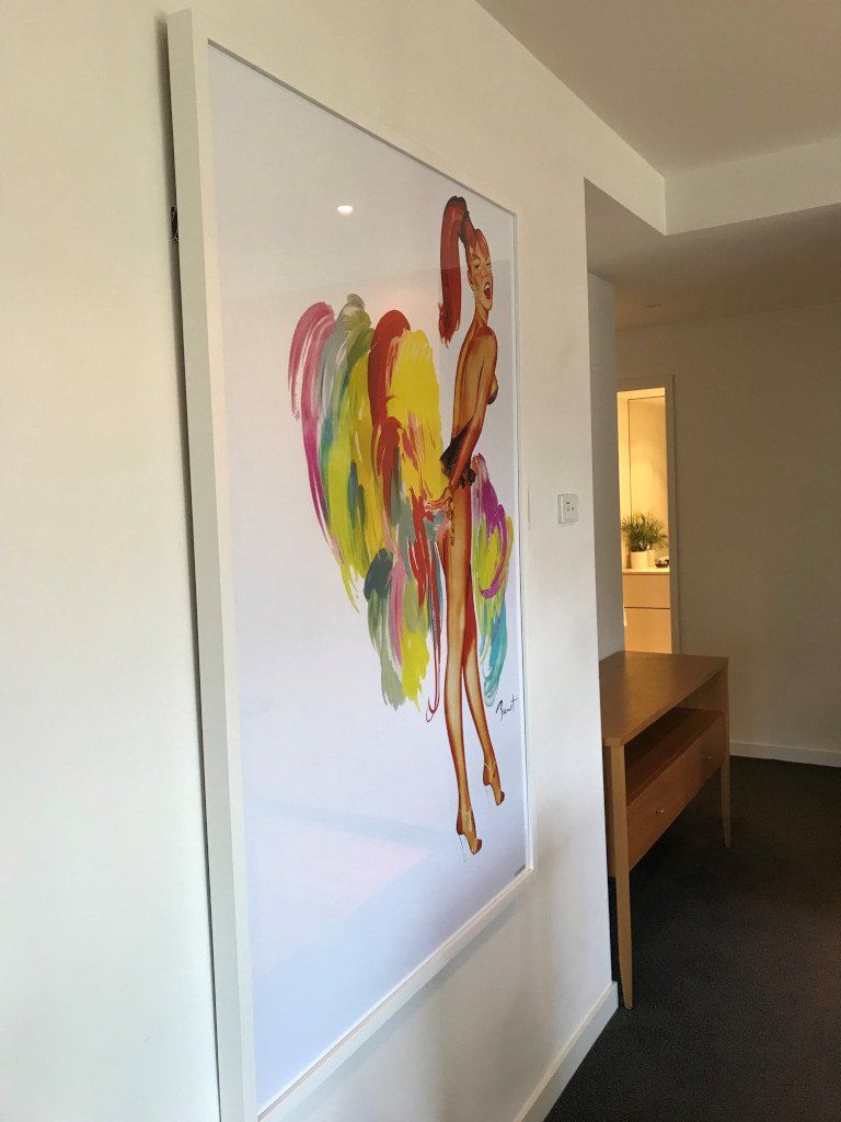 A colorful painting of a rooster is hanging on a white wall