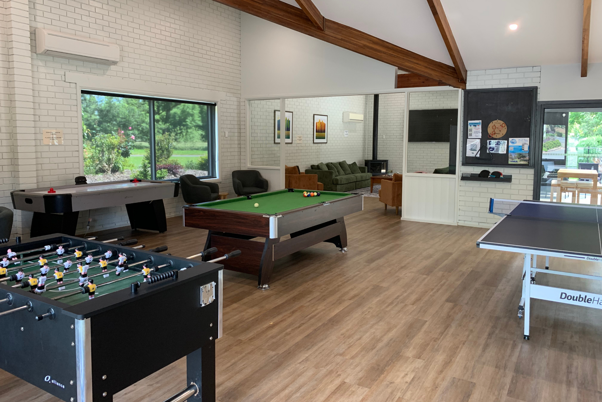 A large room with a pool table , foosball table , and ping pong table.