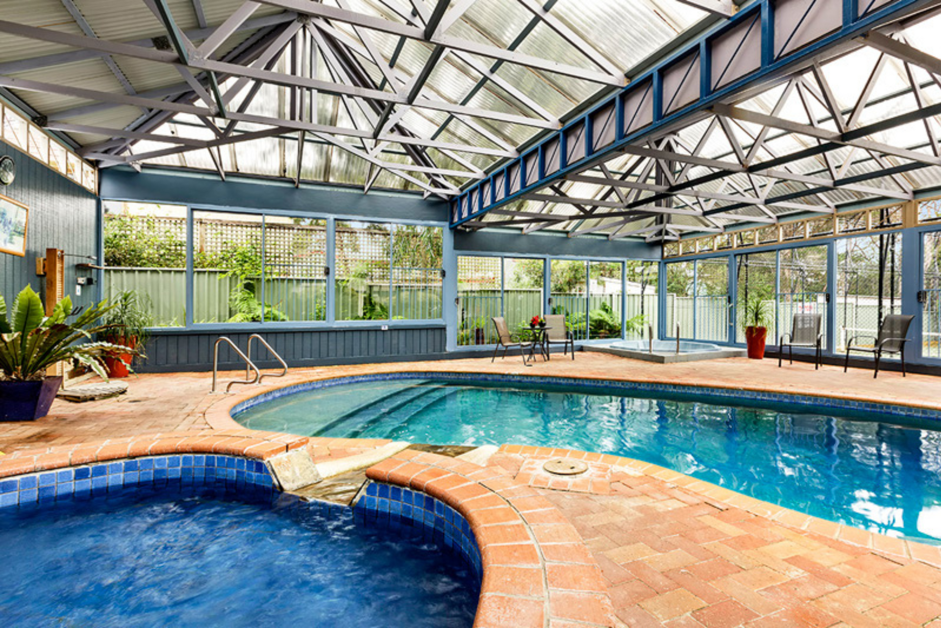 A large indoor swimming pool with a hot tub next to it.