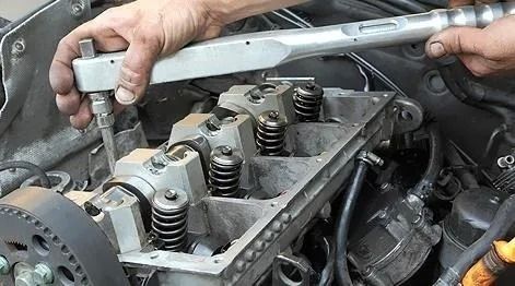 Persona que utiliza una llave dinamométrica en el motor de un automóvil, apretando los pernos en la culata.