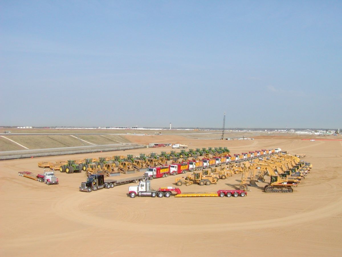 A lot of construction vehicles are parked in a field