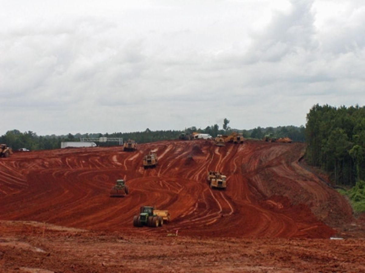 A group of tractors are driving down a dirt road
