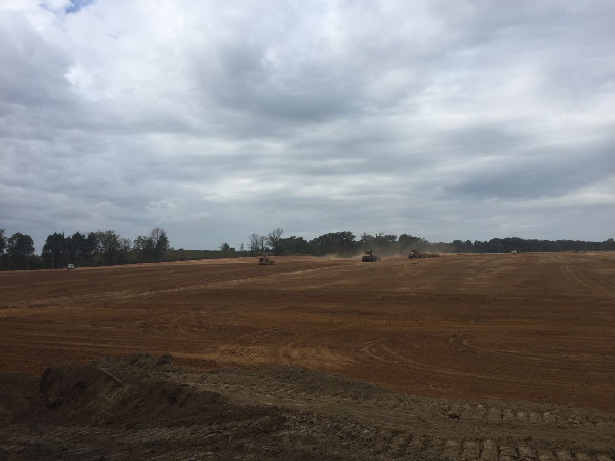A large dirt field with a cloudy sky in the background.