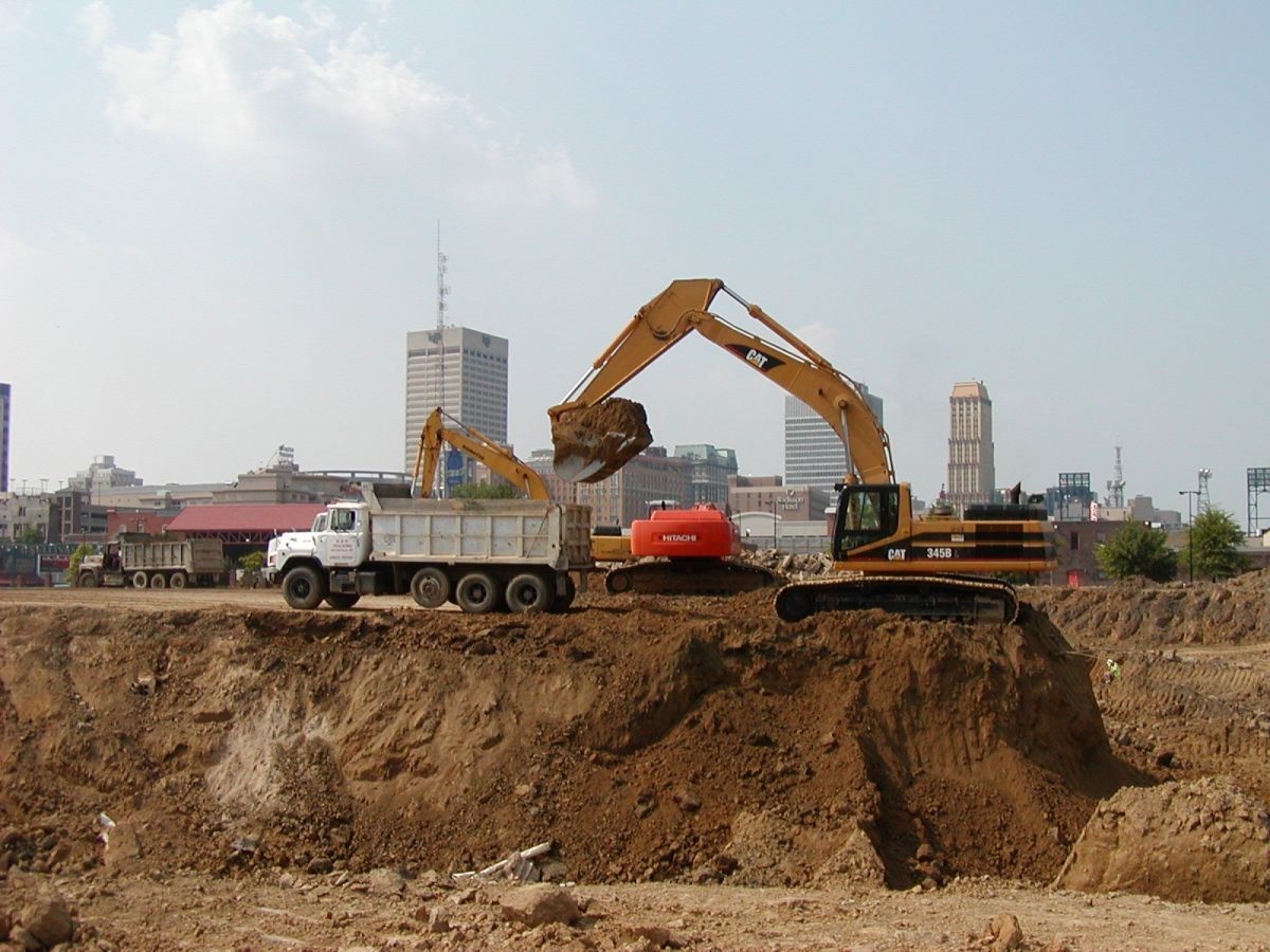 A dump truck is being loaded with dirt by an excavator