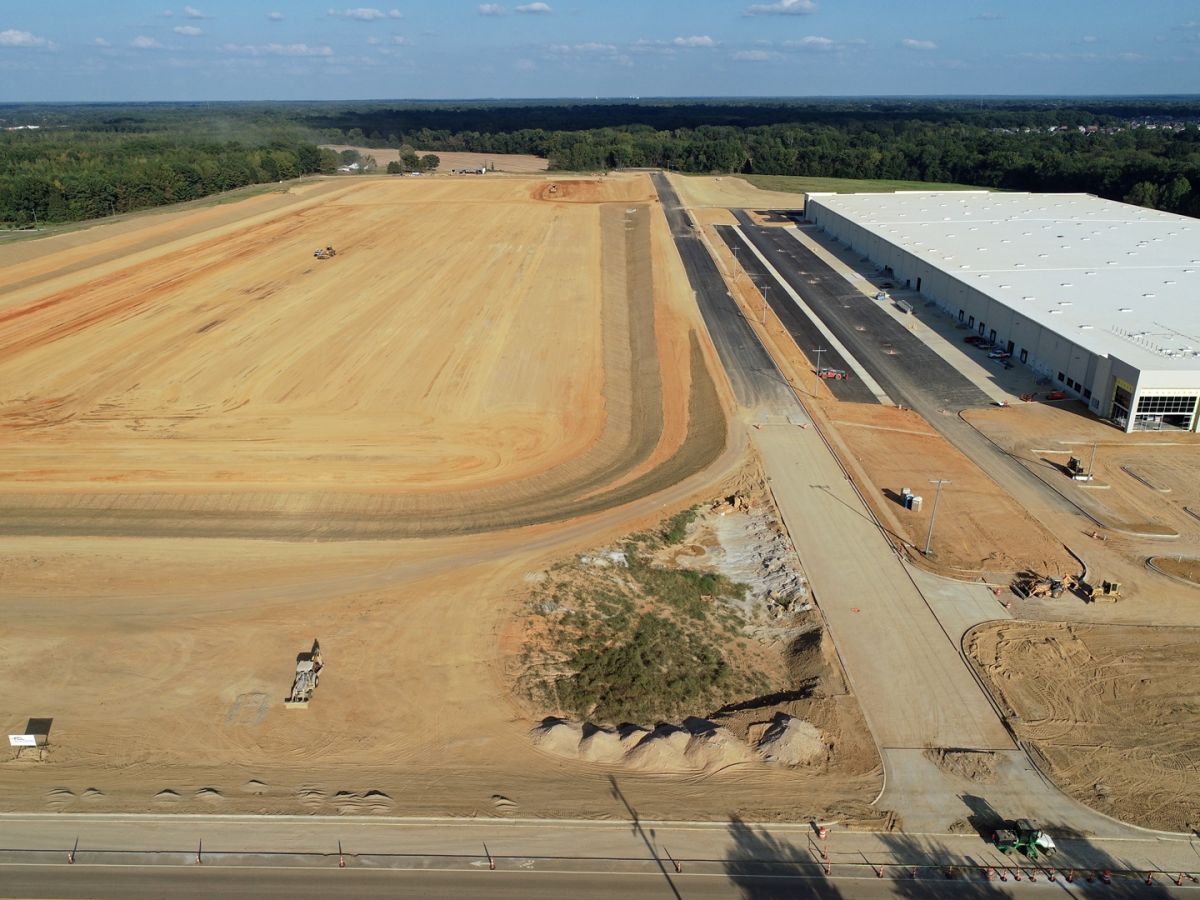 An aerial view of a construction site with a large building in the background.