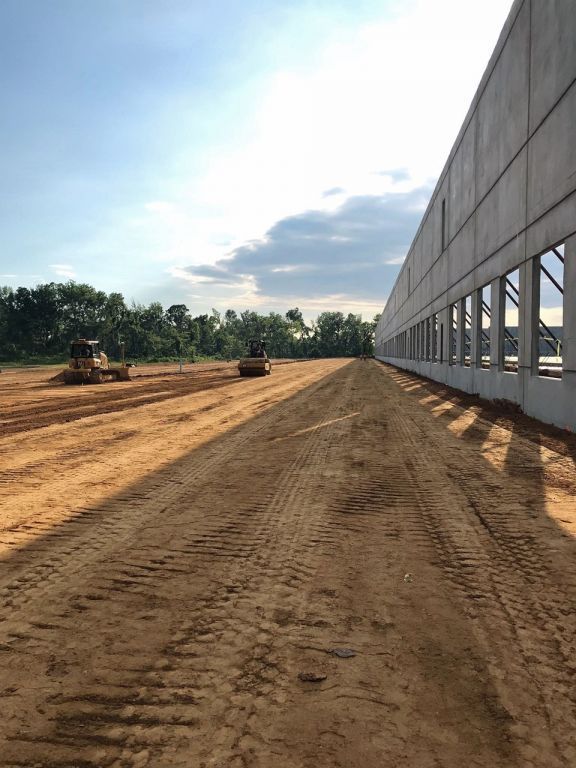 A large building is being built on a dirt road.