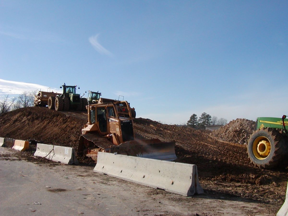 A green john deere tractor is parked in front of a pile of dirt