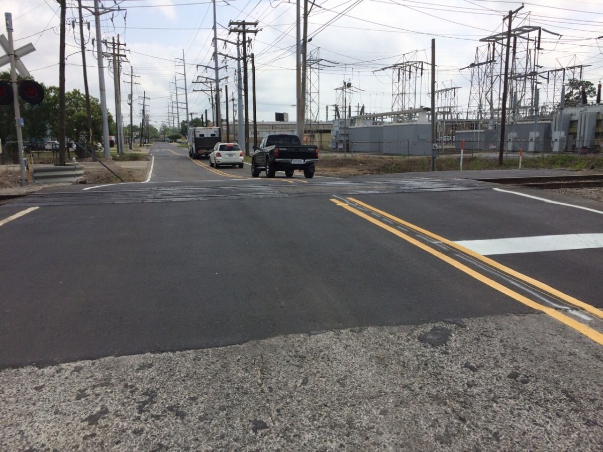 A truck is driving down a road next to a railroad crossing.