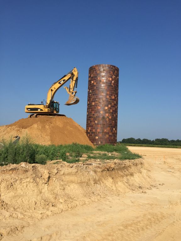 A large yellow excavator is working on a large pile of dirt.