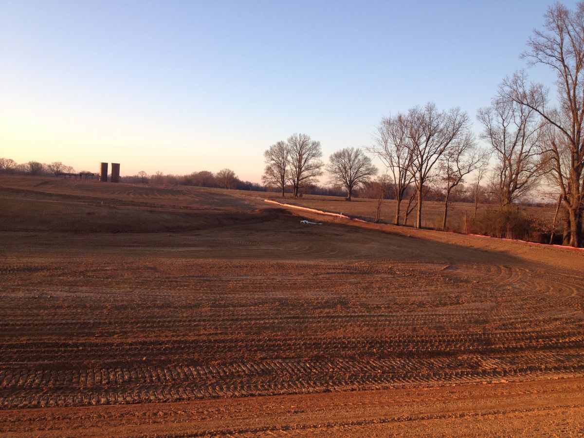 A field with trees and silos in the background