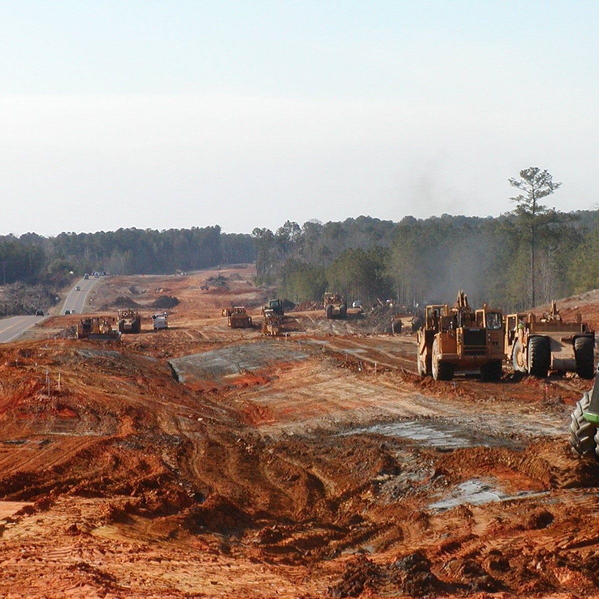 A group of construction vehicles are working on a dirt road.