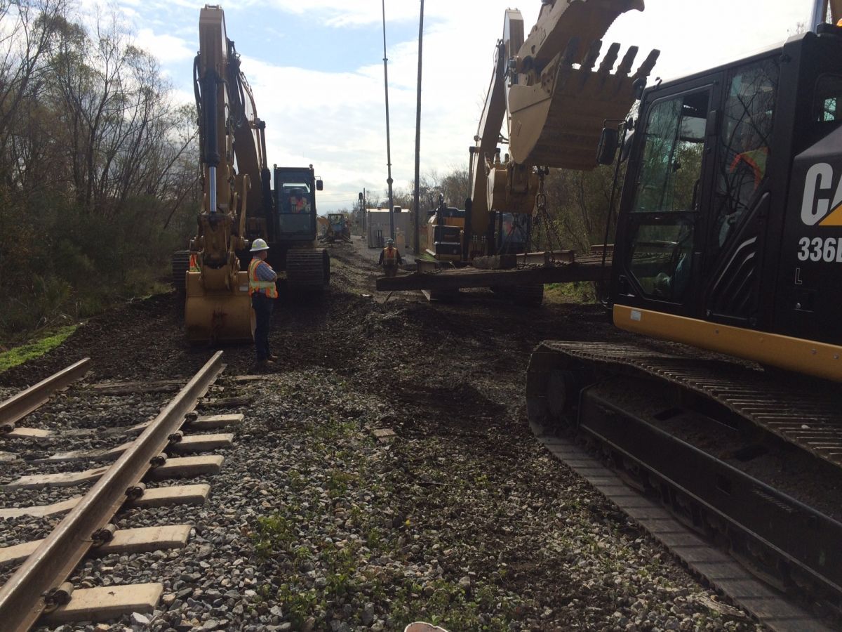 A cat excavator is on the train tracks