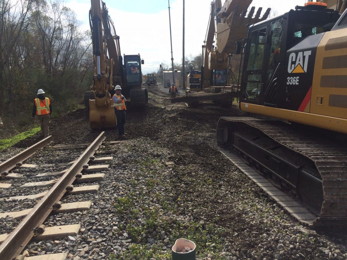 A cat excavator is parked on a train track