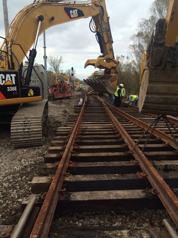 A cat excavator is working on train tracks