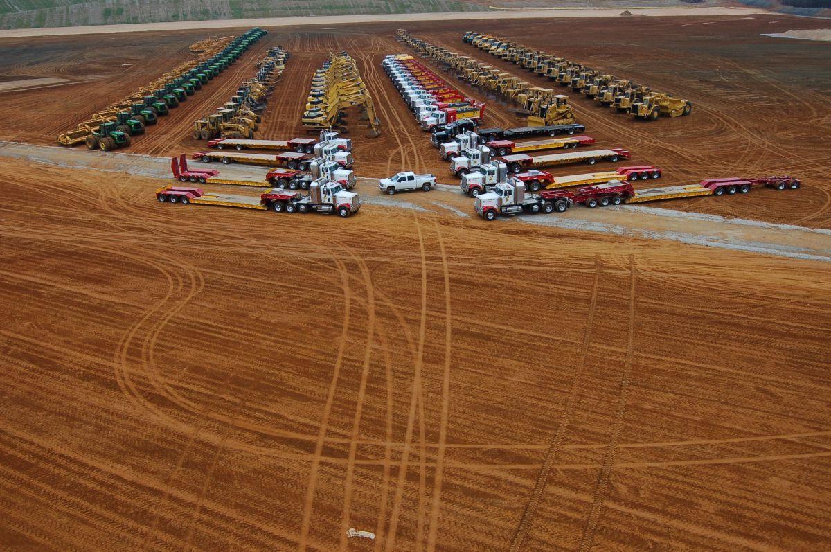 A bunch of trucks are parked in a dirt field.