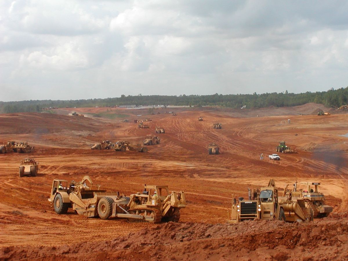 A group of tractors are working on a dirt road.