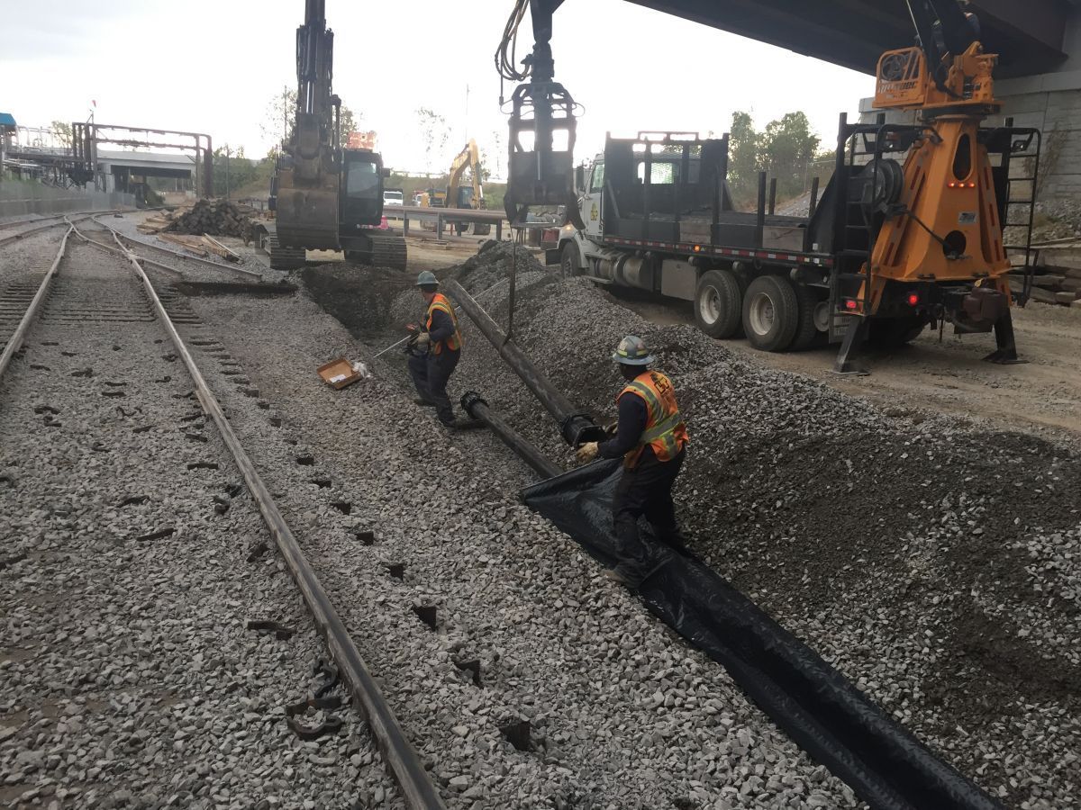 A group of construction workers are working on train tracks.