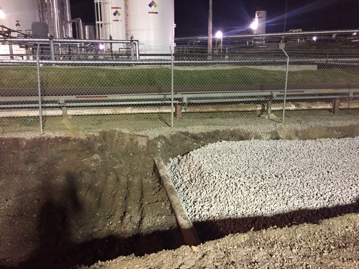 A large pile of gravel is sitting in front of a fence