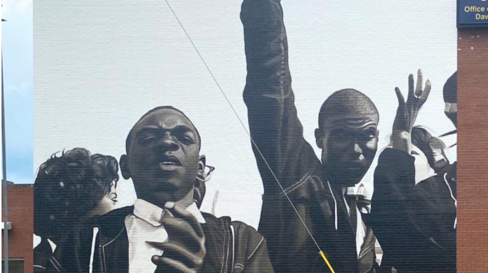 Mural of a crowd, some with arms raised. Mostly black and white.