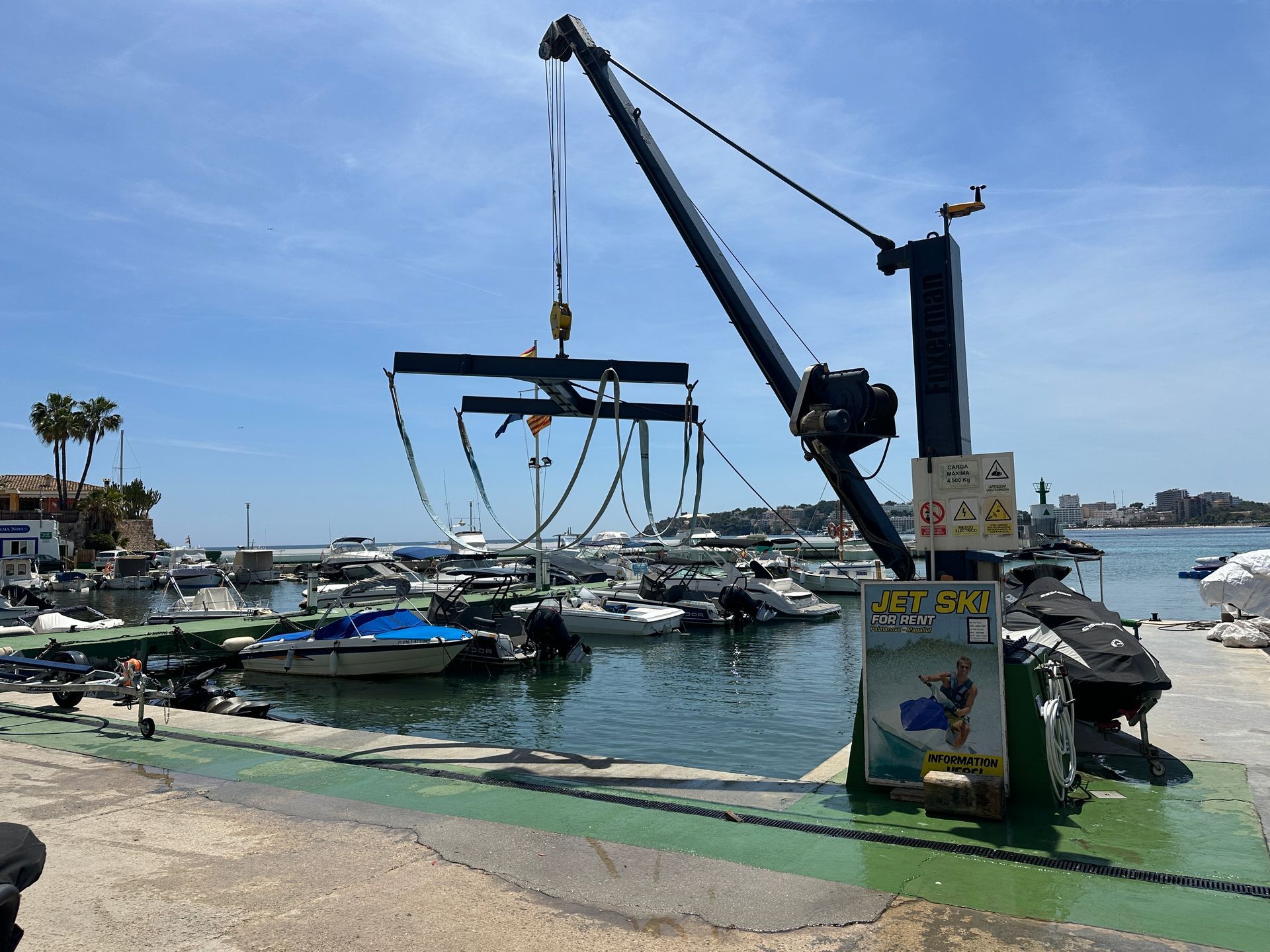 Un barco está siendo levantado por una grúa en un puerto deportivo.