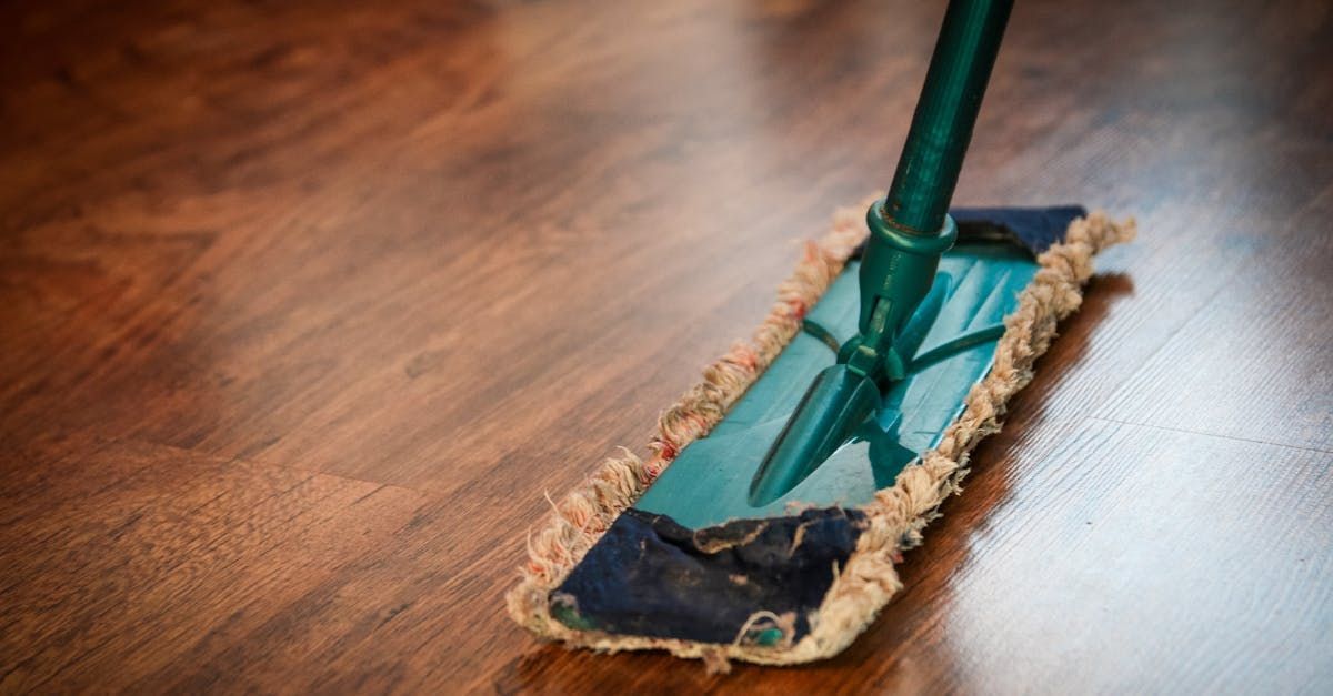 A mop is being used to clean a wooden floor.