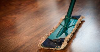 A mop is being used to clean a wooden floor.