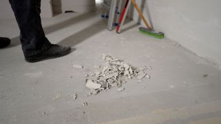 A person is cleaning the floor with a broom and a ladder.