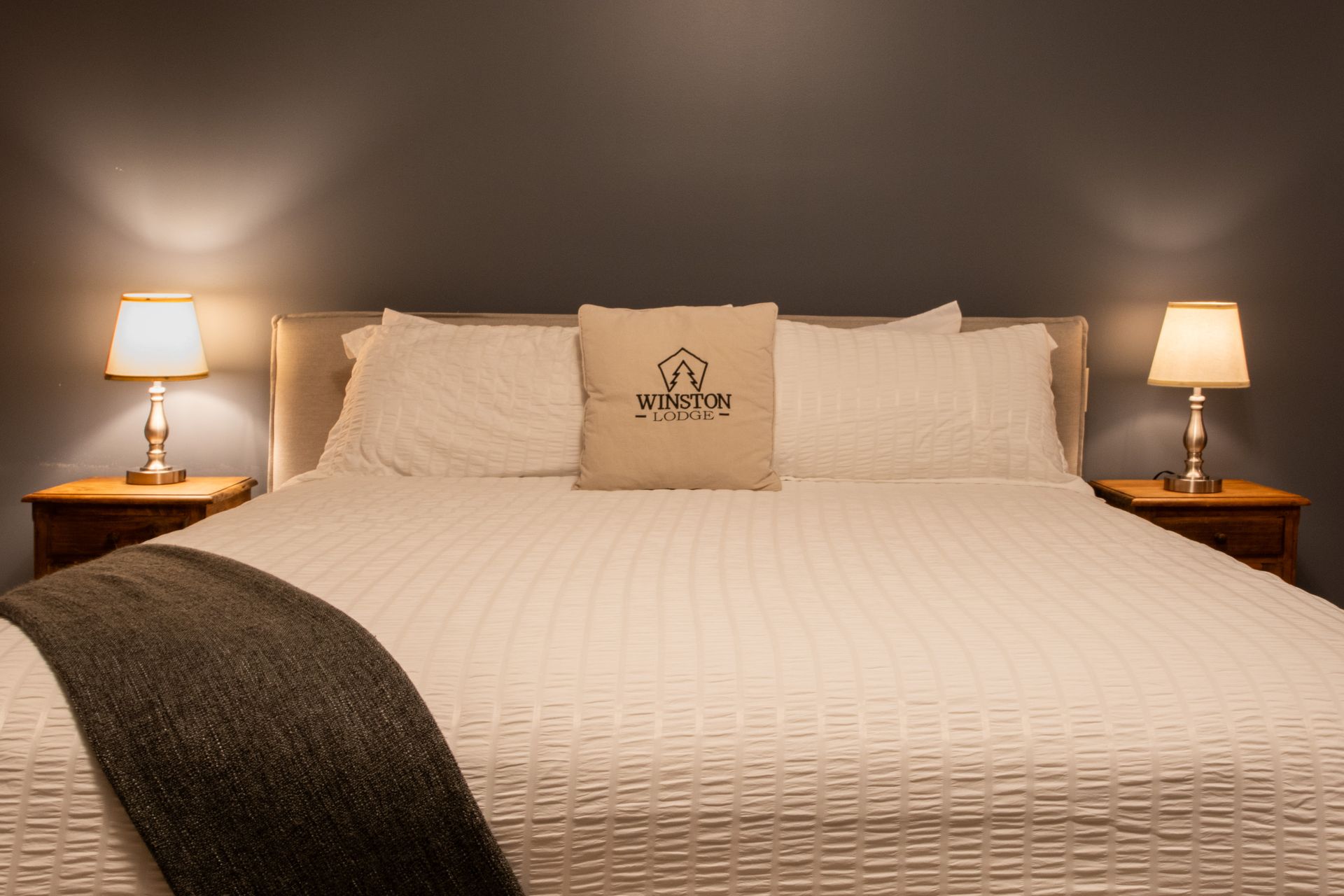 A bedroom with a bed , two lamps and a pillow with a house on it