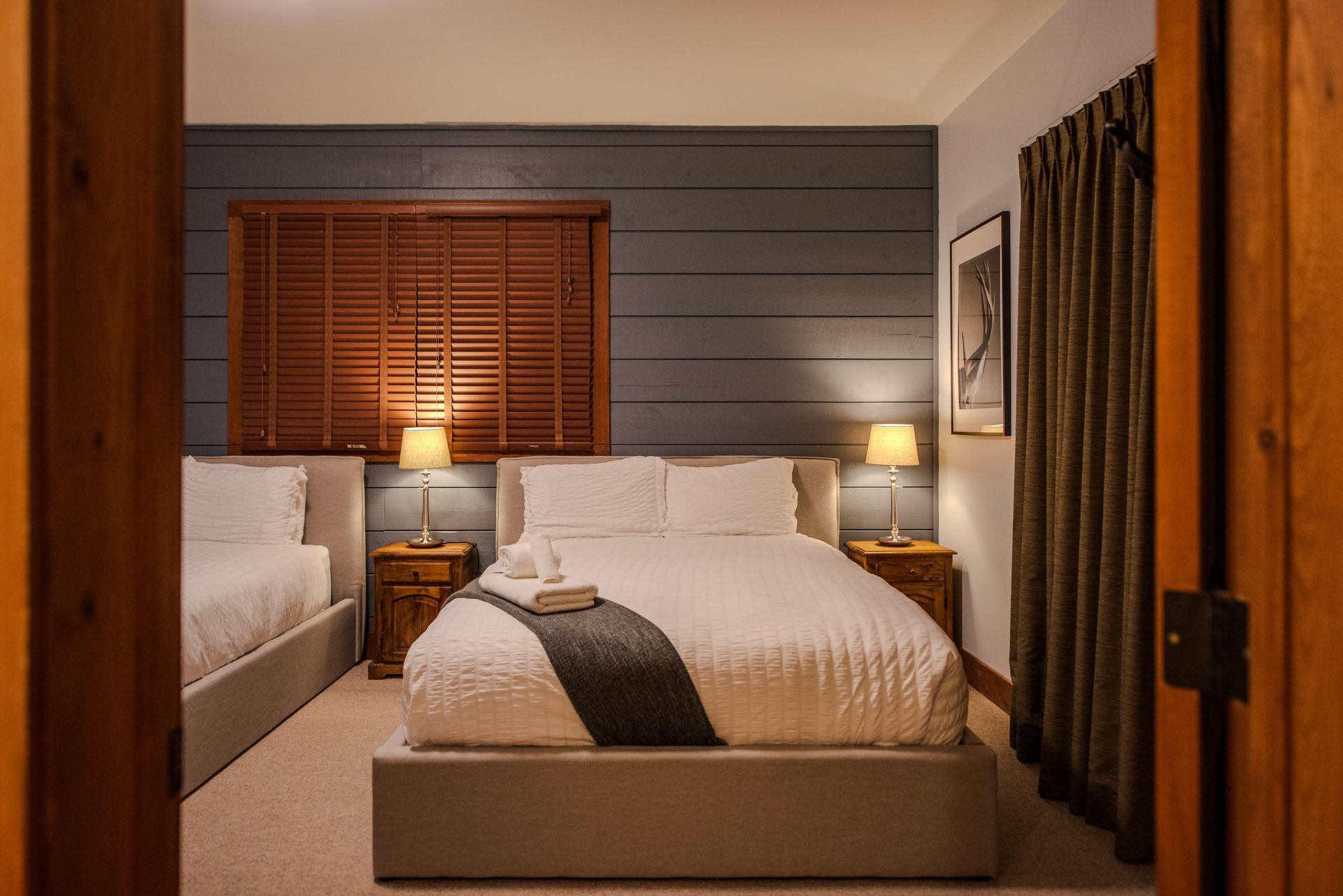 A bedroom with two beds and a window with blinds.