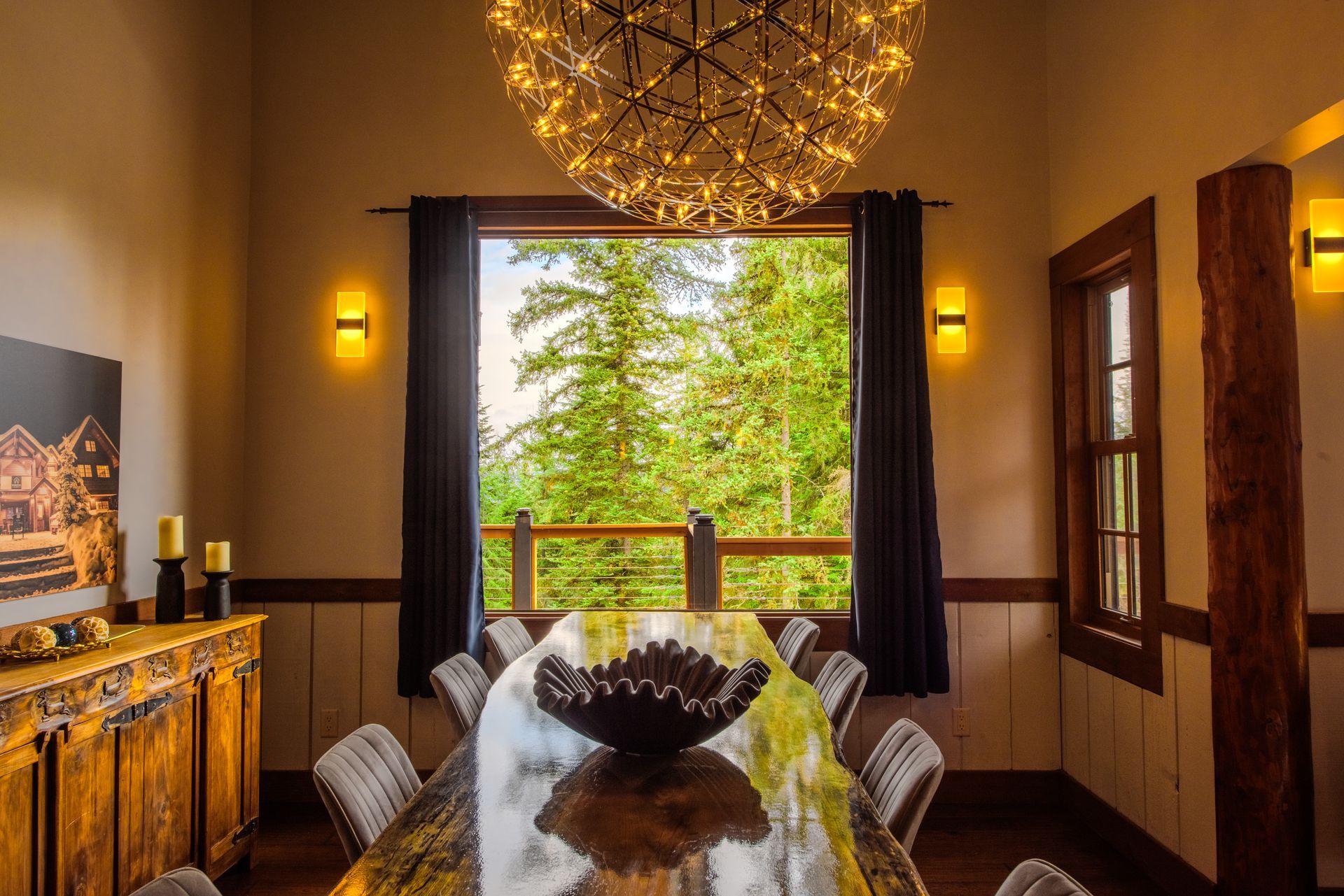 A dining room with a large table and chairs and a chandelier hanging from the ceiling.