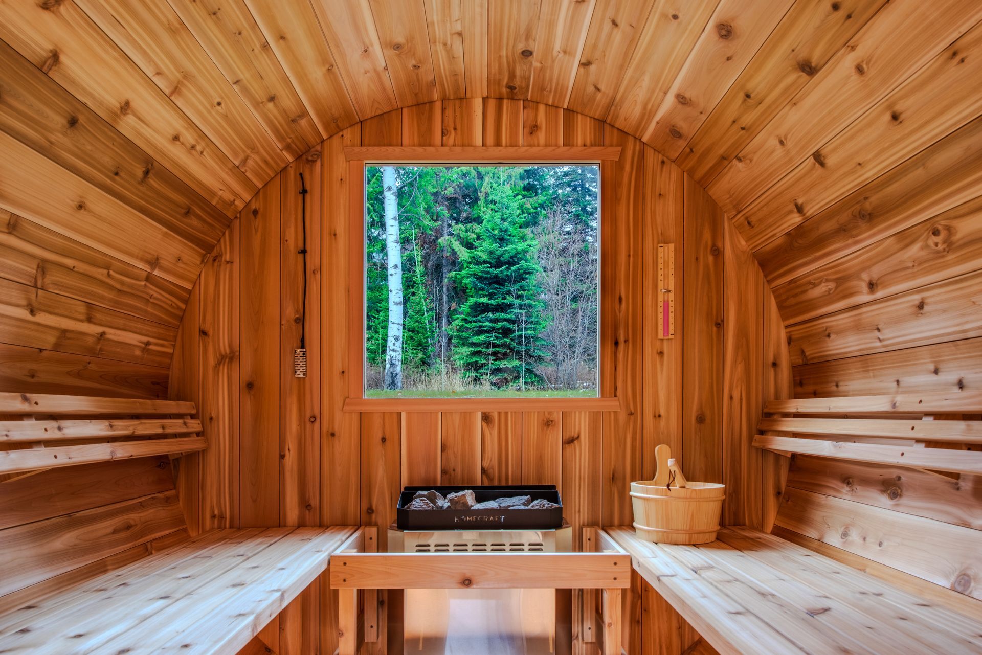 The inside of a wooden sauna with a window and a bucket.