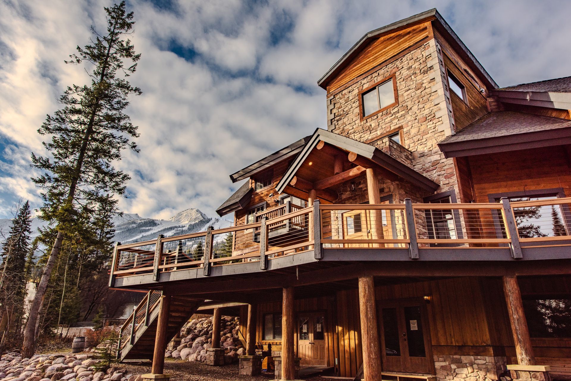 A large stone house with a large deck and stairs