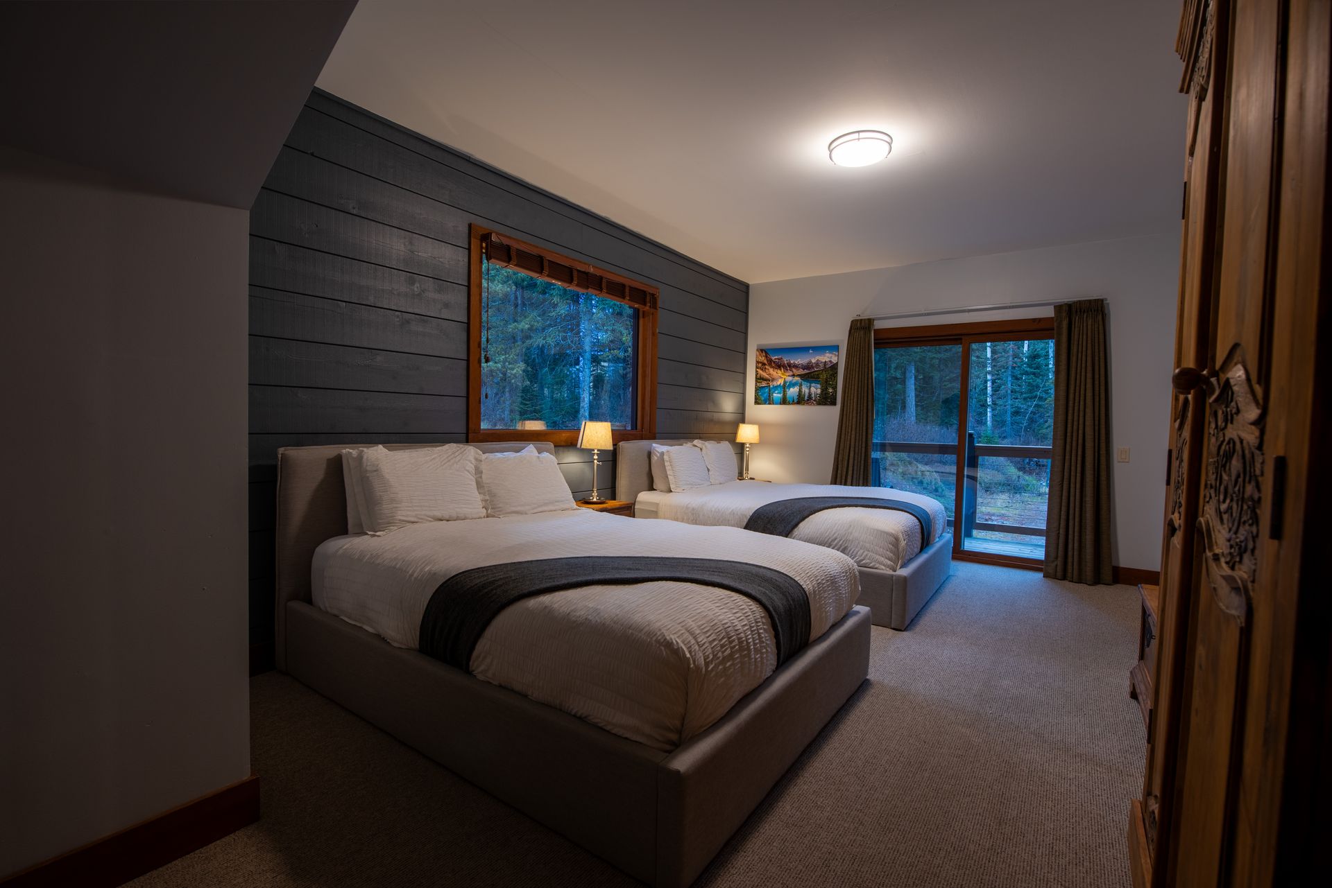 A hotel room with two beds and a sliding glass door.