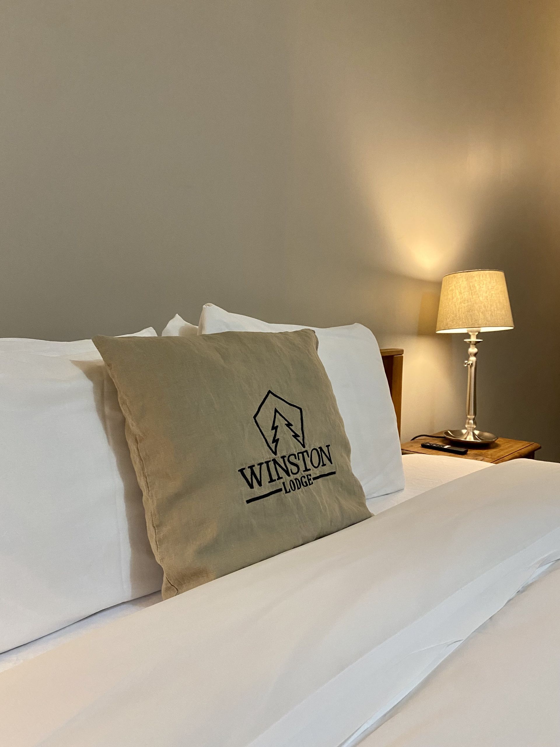 A bed with white sheets and a pillow that says ' winds ' on it